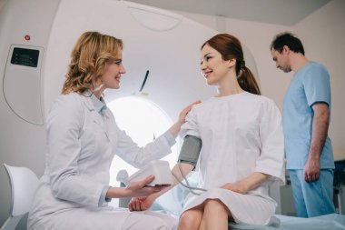 ct tarayıcı ayarlama asistan iken tonometre ile hastaların kan basıncı ölçme gülümseyen doktor