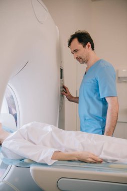 handsome attentive radiologist operating mri machine during patients diagnostics clipart