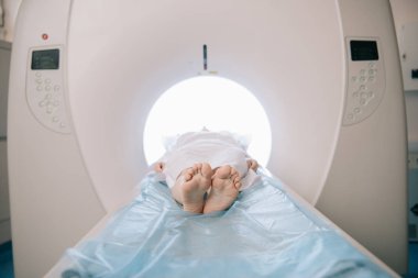 patient lying on computed tomography scanner bed during diagnostics clipart