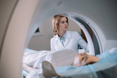 selective focus of attentive radiologist operating mri machine during patients diagnostics clipart
