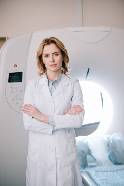 beautiful radiologist standing near ct scanner with crossed arms and looking at camera 