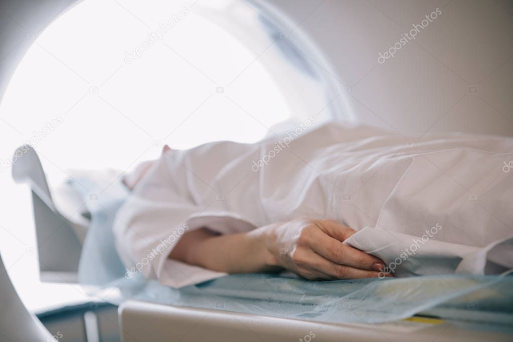 Selective focus of woman lying on ct scanner table during tomography diagnostics
