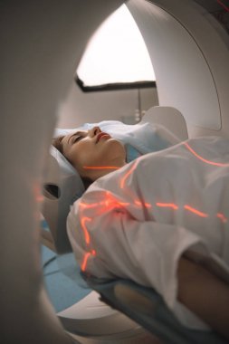 Tomografi taraması sırasında tomografi yatağında yatan genç bir kadın.
