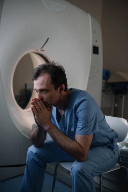 düşünceli radyolog hastanede bilgisayarlı tomografi tarayıcı yakınında oturan ve uzağa bakarak