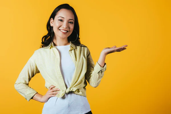 Sorrindo Asiático Menina Apresentando Algo Isolado Amarelo — Fotografia de Stock