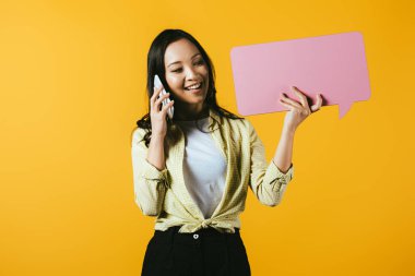 akıllı telefon konuşurken ve pembe konuşma balonu tutan gülümseyen asyalı kız, sarı izole