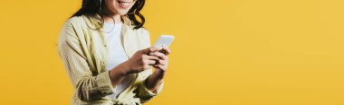 sarı izole akıllı telefon kullanarak genç kadının kırpılmış görünümü  