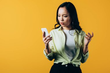 sarı izole akıllı telefon kullanarak düşünceli genç asyalı kadın  