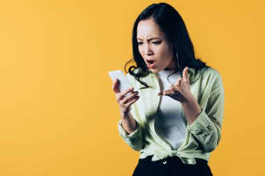 sarı izole akıllı telefon konuşurken kızgın asyalı genç kadın 