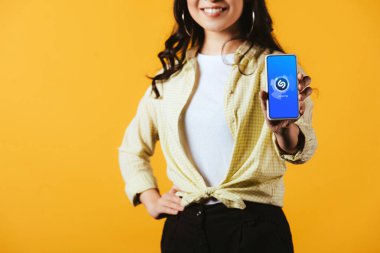 Kiev, Ukrayna - 16 Nisan 2019: shazam uygulaması ile akıllı telefon gösteren esmer kız kırpılmış görünümü, sarı izole