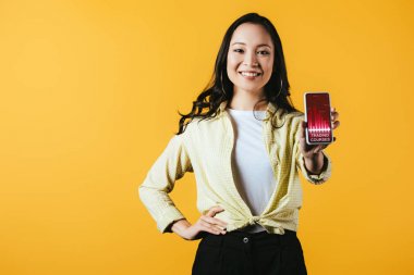 sarı izole ticaret kursları ile akıllı telefon gösteren mutlu asyalı kız