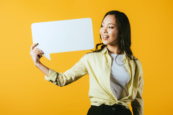 happy asian woman holding speech bubble, isolated on yellow 