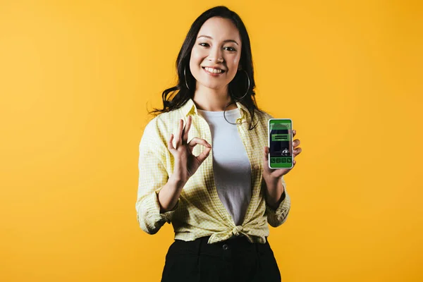 Happy Asian Girl Showing Sign Smartphone Booking App Isolated Yellow — Stock Photo, Image