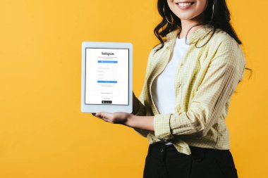 Kiev, Ukrayna - 16 Nisan 2019: instagram uygulaması ile dijital tablet gösteren gülümseyen kız kırpılmış görünümü, sarı izole