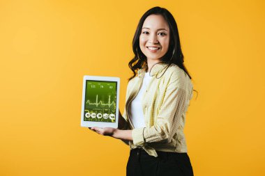mutlu asyalı kız sağlık uygulaması ile dijital tablet gösteren, sarı izole