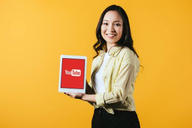 Kiev, Ukrayna - 16 Nisan 2019: youtube uygulaması ile dijital tablet gösteren güzel asyalı kız, sarı izole