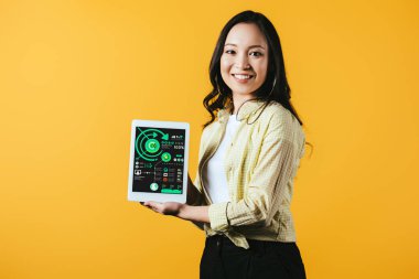 mutlu asyalı kız infografik uygulaması ile dijital tablet gösteren, sarı izole