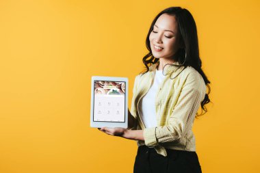 Kiev, Ukrayna - 16 Nisan 2019: foursquare uygulaması ile dijital tablet gösteren güzel asyalı kız, sarı izole