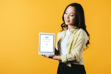 Kiev, Ukrayna - 16 Nisan 2019: güzel asyalı kız skype uygulaması ile dijital tablet gösteren, sarı izole