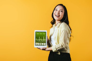 sağlık uygulaması ile dijital tablet gösteren gülümseyen asyalı kız, sarı izole