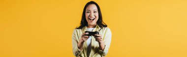 Kiev, Ukrayna - 16 Nisan 2019: joystick ile video oyunu oynayan mutlu Asyalı kadın, sarı izole 