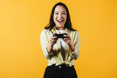 Kiev, Ukrayna - 16 Nisan 2019: joystick ile video oyunu oynayan heyecanlı Asyalı kadın, sarı izole 