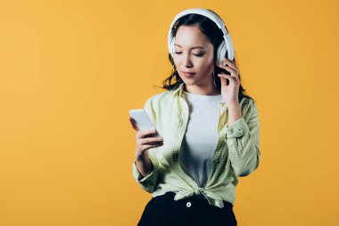 asyalı kız kulaklık ve akıllı telefon ile müzik dinleme, sarı izole