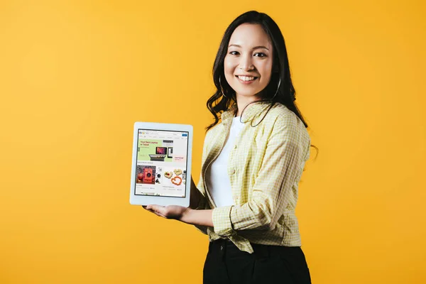 乌克兰 2019年4月16日 微笑的亚洲女孩显示数字平板电脑与Ebay应用程序 隔离在黄色 — 图库照片