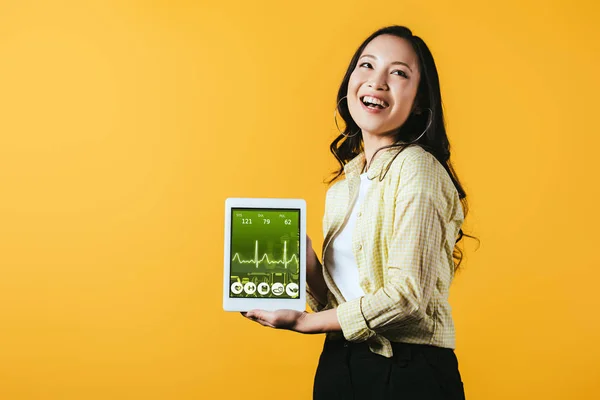 健康アプリでデジタルタブレットを示す笑顔のアジアの女の子 黄色で隔離 — ストック写真