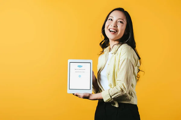 乌克兰 2019年4月16日 微笑的亚洲女孩显示数字平板电脑与Skype应用程序 隔离在黄色 — 图库照片