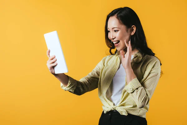 Улыбающаяся Азиатская Девушка Машет Делает Видеозвонок Цифровой Планшет Изолированный Желтый — стоковое фото