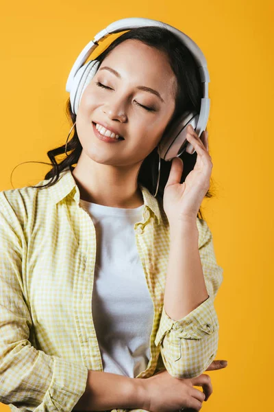 Glimlachend Aziatisch Meisje Luisteren Muziek Met Koptelefoon Geïsoleerd Geel — Stockfoto