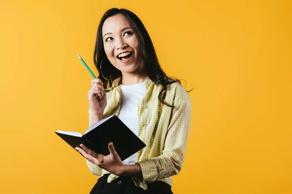 Glimlachend Aziatisch Meisje Met Notitieboekje Pen Geïsoleerd Geel — Stockfoto