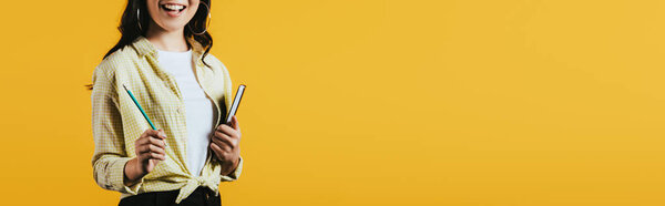 cropped view of girl with notebook and pen, isolated on yellow 