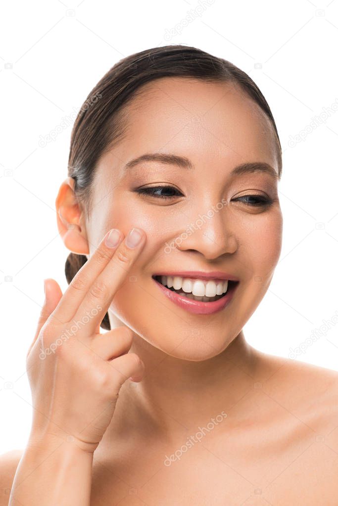 attractive smiling asian girl applying cream, isolated on white