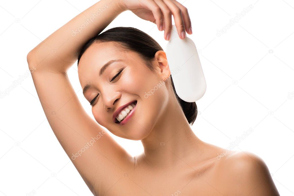 happy asian woman with closed eyes holding bottle of lotion, isolated on white