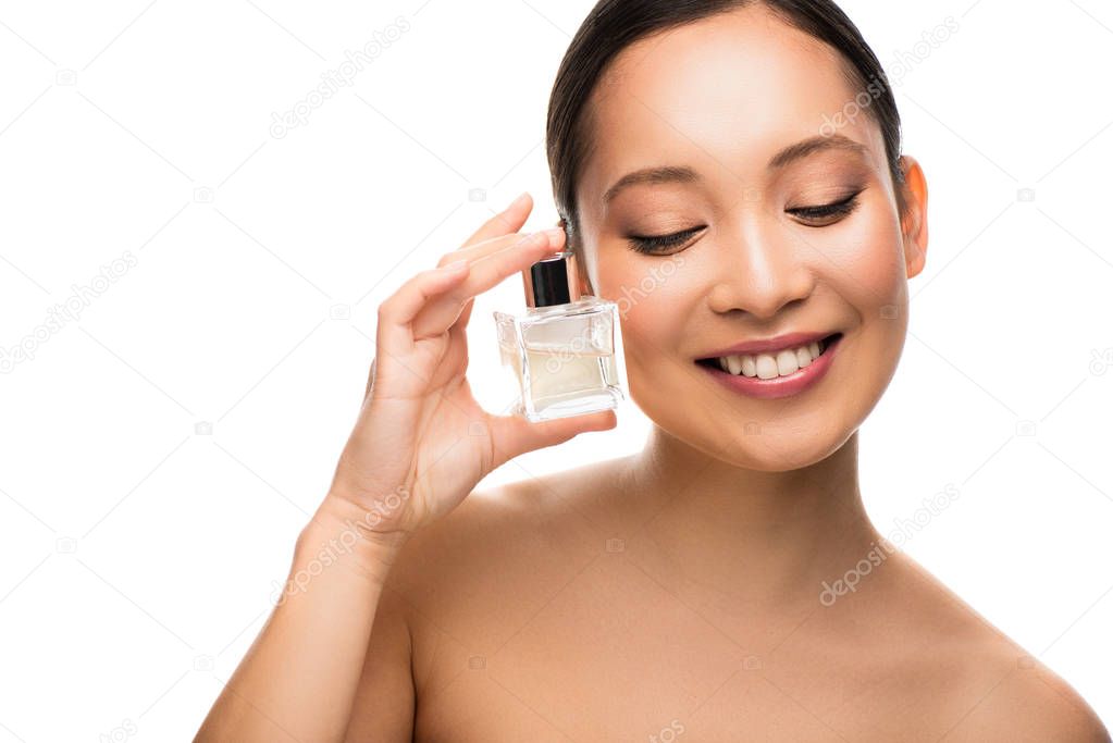 smiling asian woman holding perfume, isolated on white