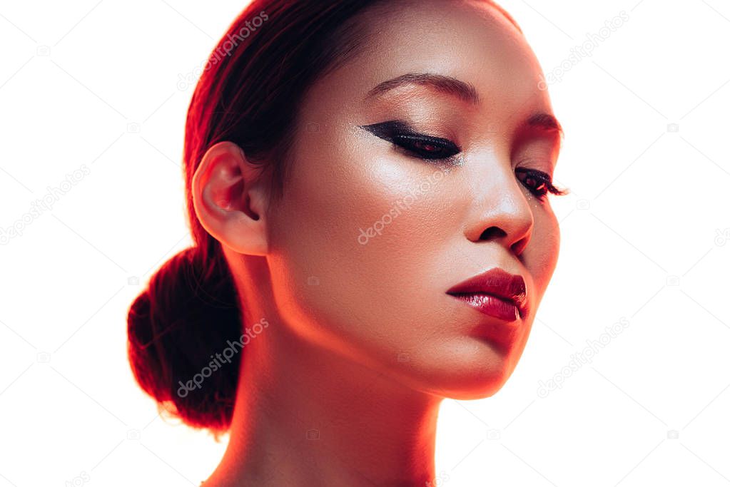 brunette asian woman with makeup in red light, isolated on white