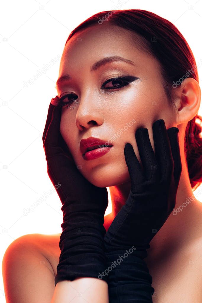 brunette asian girl in black gloves with makeup in red light, isolated on white