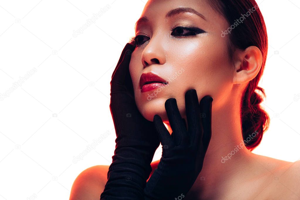 attractive tender asian woman in black gloves with makeup in red light, isolated on white