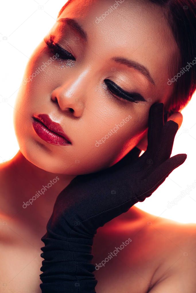 tender asian girl in black gloves with makeup in red light, isolated on white