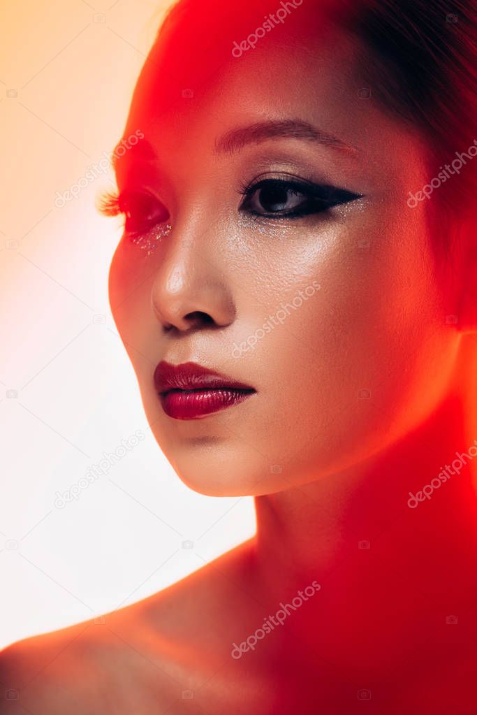 attractive asian girl with makeup in red light, toned picture