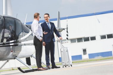 Helikopter yanında bavul ile resmi giyim ve işadamı pilot