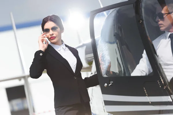 Mujer Negocios Ropa Formal Hablando Smartphone Cerca Helicóptero Con Piloto —  Fotos de Stock