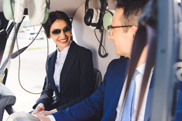 деловая женщина и бизнесмен в формальной одежде сидят в кабине вертолета
