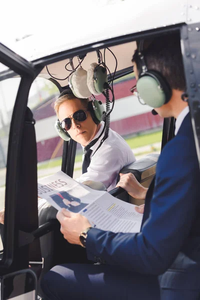 Helikopter kabin içinde gazete ile kulaklık ve işadamı pilot