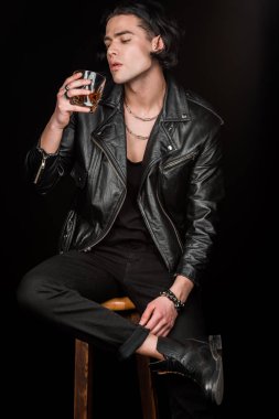 yakışıklı adam sandalyede oturan ve viski cam siyah izole bakarak  