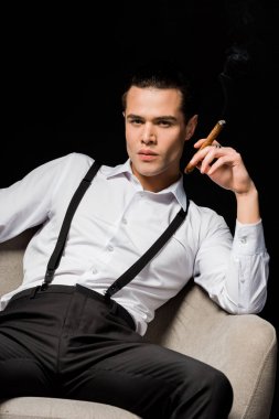 siyah izole koltukta otururken puro tutan yakışıklı adam 