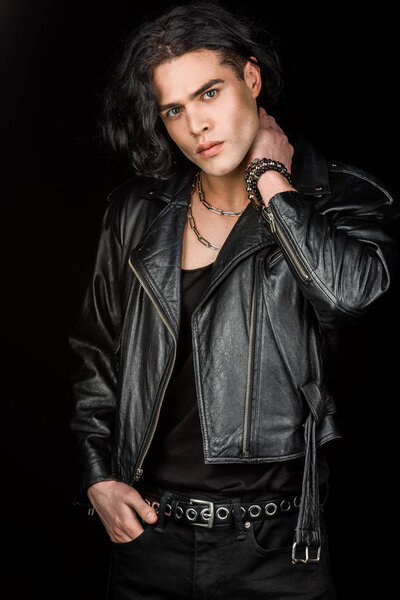 Красивый мужчина, стоящий с рукой в кармане и смотрящий на камеру, изолированную на черном
 