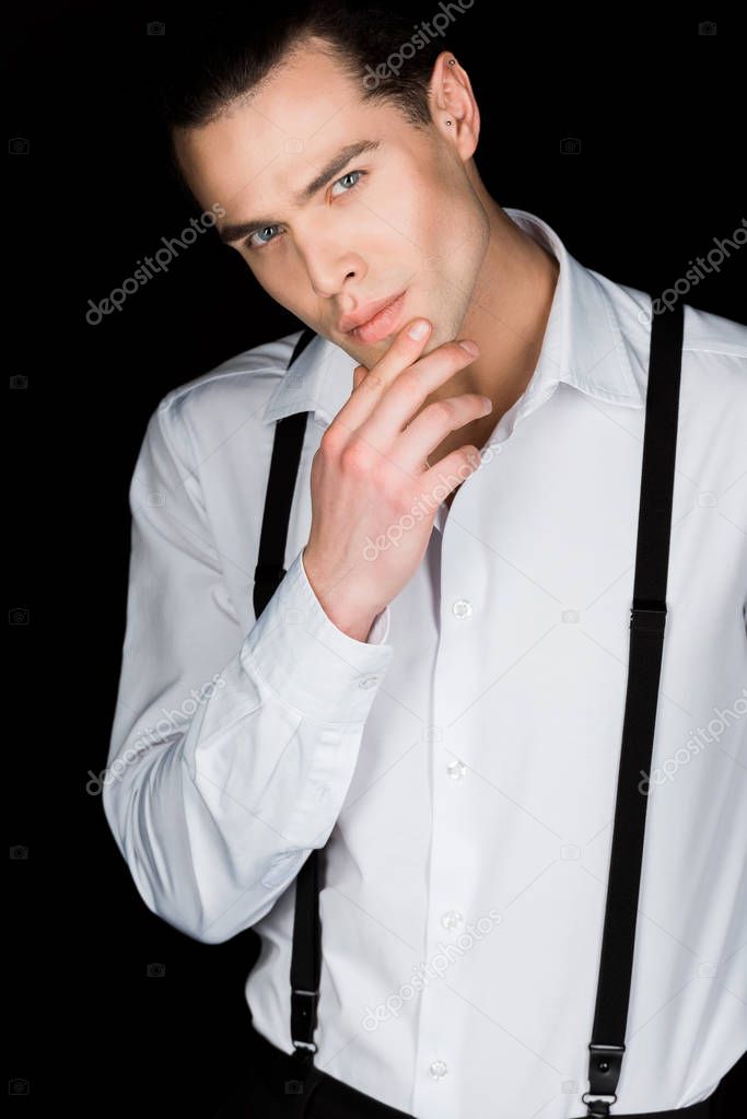 handsome man in white shirt touching face isolated on black 